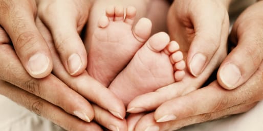 Parent hands supporting baby feet